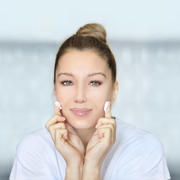 Frau mit Creme auf den Fingerspitzen über 20 Jahre alt